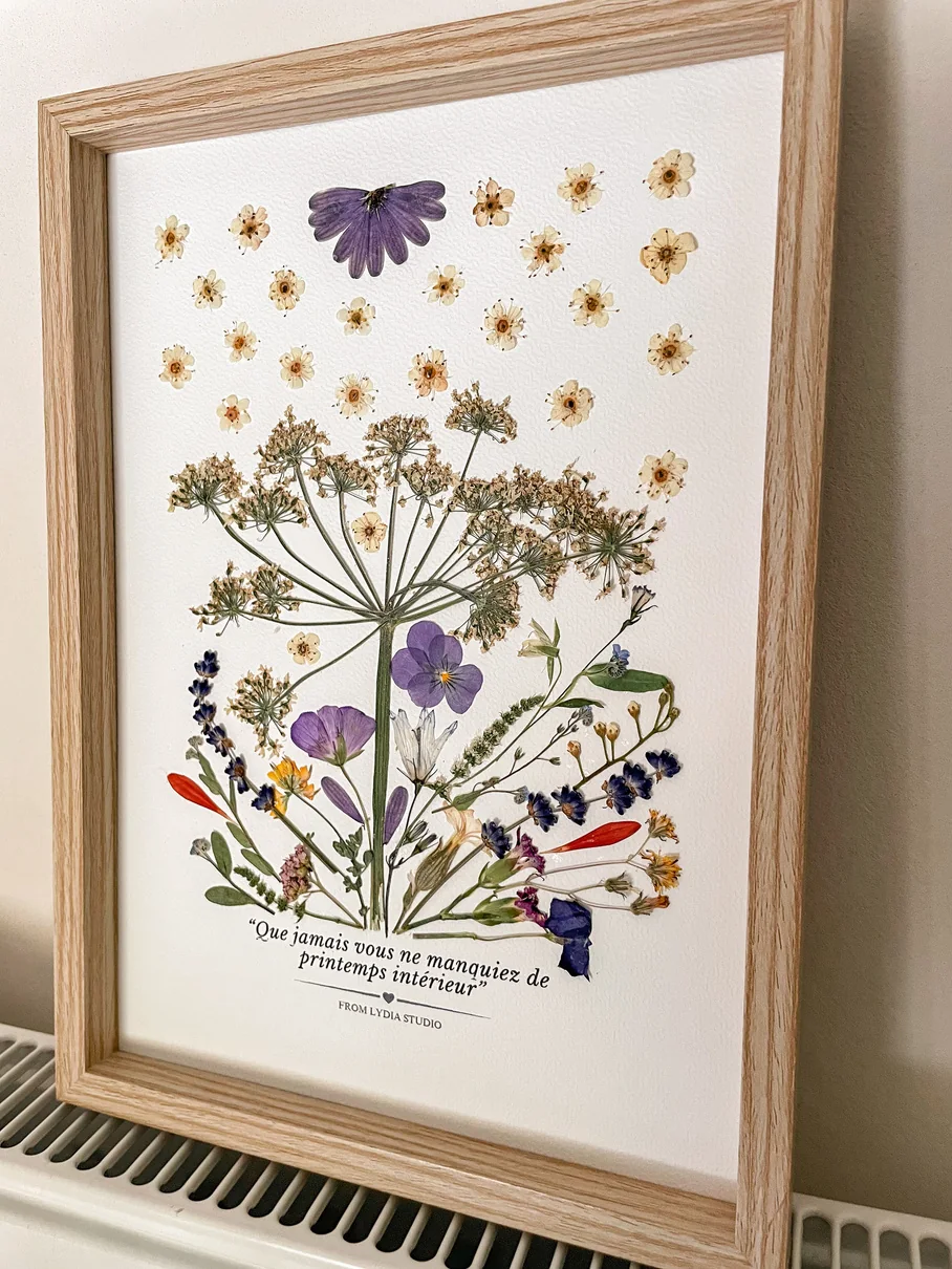 Tableau de fleurs pressées bleues, jaunes et roses dans un cadre en bois clair